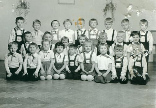 THE CZECHOSLOVAK SOCIALIST REPUBLIC - CIRCA 1960s: Retro photo shows pupils in the classroom. They pose for a group photography. Vintage black and white photography. Original image is damaged.