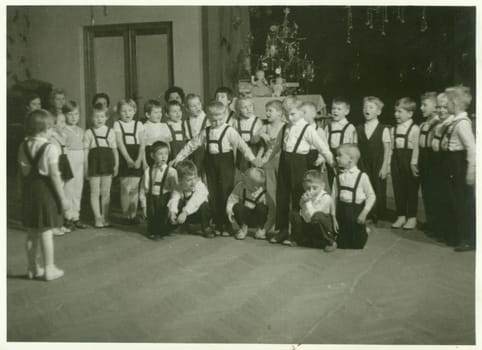 THE CZECHOSLOVAK SOCIALIST REPUBLIC - CIRCA 1960s: Retro photo shows small pupils in the classroom. Schoolmates participate in school performance during Christmas time. Vintage black and white photography.