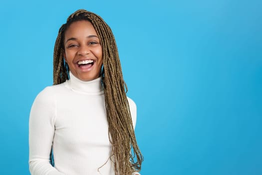 Studio portrait with blue background of a smiley african beauty woman looking at camera