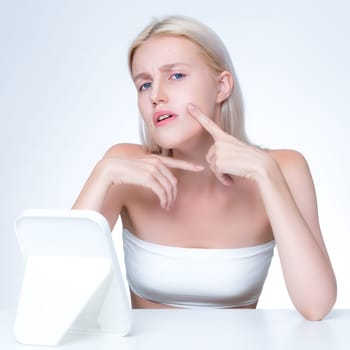 Acne problem troubling personable worried woman with natural beauty skin checking her face squeezing pimple spots in isolated background. Copyspace for blemish skincare treatment problem.