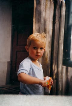 THE CZECHOSLOVAK SOCIALIST REPUBLIC - CIRCA 1980s: Retro photo shows cute small boy with open juice box. Vintage color photography.