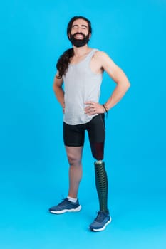 Vertical Studio portrait with blue background of a sportive man standing and smiling with a leg prosthesis