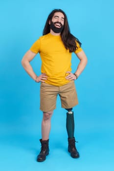 Vertical studio portrait with blue background of a happy man with prosthesis leg laughing while posing in studio