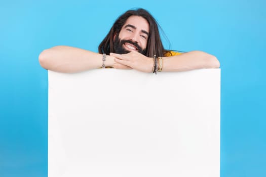Studio portrait of a happy smiley man with long hair holding a board with blank space