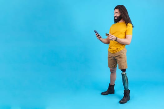 Studio portrait with blue background and copy space of a man with prosthesis on his leg