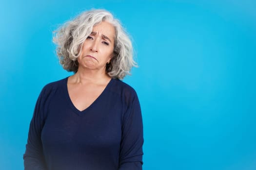 Studio portrait with copy space and blue background of a Sad mature woman about to cry