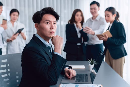 Portrait of focus young successful confident male manager, executive wearing business wear in harmony office arm crossed with blurred meeting background of colleagues, office worker.