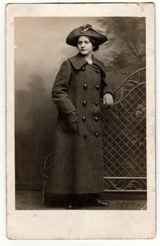 PRAGUE, THE CZECHOSLOVAK REPUBLIC - CIRCA 1940s: Vintage photo shows woman wears ladies hat and long pea coat- long reefer jacket. Retro black - white photography.