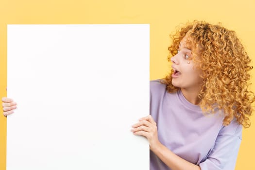 Studio image with yellow background of a woman looking to a blank panel