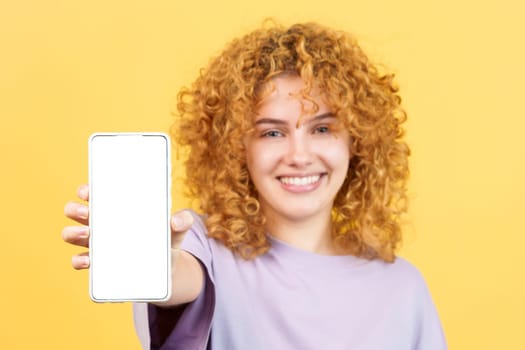 Studio image with yellow background of the blank screen of the mobile held by a young woman