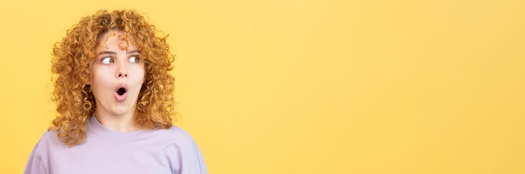 Panoramic studio image with yellow background of a young beauty woman with curly hair looking aside with surprised expression