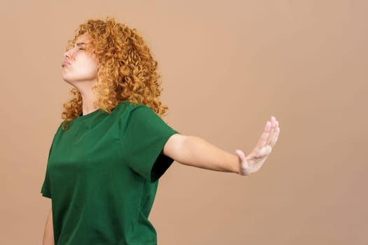 Studio image of a young woman with curly hair and casual clothing gesturing that she wants to know nothing