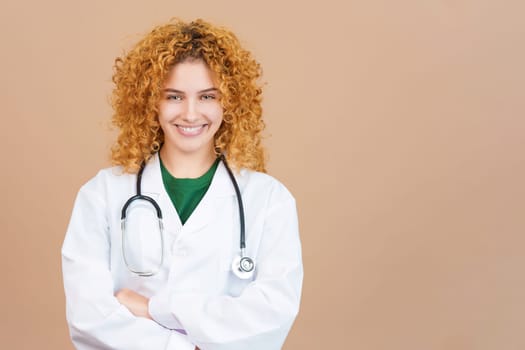 Studio image of a female young doctor with curly hair smiling at camera with the arms crossed