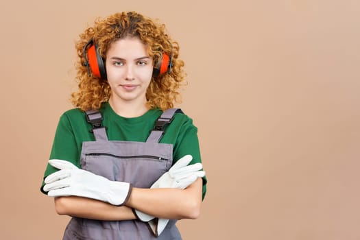 Studio image of a woman with curly hair carpentry worker with tools and work uniform