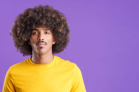 Cool african man with curly hair looking at the camera with a serious look in studio