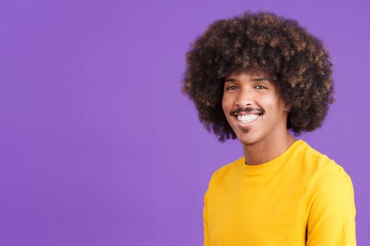 Cool african man with curly hair smiling while looking at camera in studio