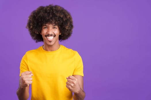 Happy african man looking at the camera and celebrating raising the fists in studio