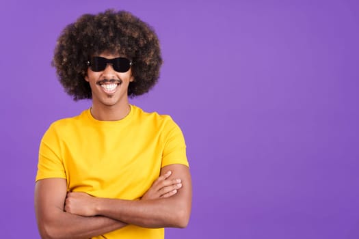Happy african man with sunglasses standing with arms crossed and smiling at the camera in studio