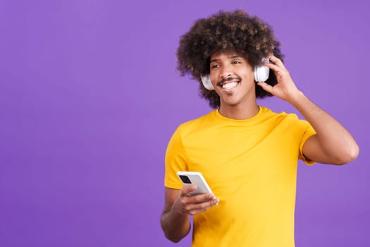 Happy african man listening to music with headphones and a mobile in studio