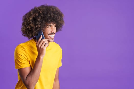 Happy and smiley african man talking to the mobile phone in studio