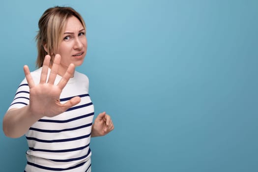 sad blonde girl waving her hand on a blue background with copy space.