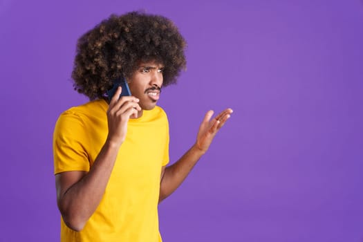 Angry african man with curly hair talking to the mobile in studio