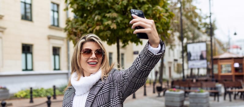 young woman model taking selfie with phone outdoors in spring.
