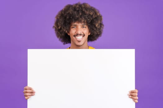 Smiley african man with curly hair holding a blank panel in studio