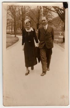 TRENCIANSKE TEPLICE, THE CZECHOSLOVAK REPUBLIC - CIRCA 1930s: Vintage photo shows a couple goes for a walk in the city park. Retro black and white photography.