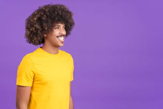 Stylish african man smiling while looking aside and standing in studio