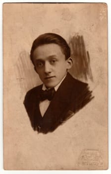 USTI NAD ORLICI, THE CZECHOSLOVAK REPUBLIC - CIRCA 1930s: Vintage photo shows a head of a young man. Original retro black and white photography. The jacket and bow tie are drawn to the head.