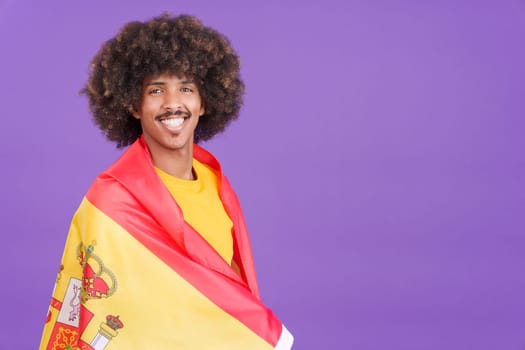African man smiling at the camera wrapping with a spanish flag in studio