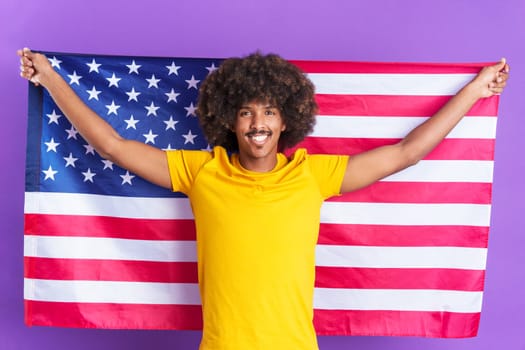 Happy african man raising a north america national flag while looking at the camera in studio