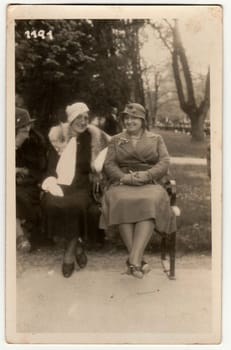 TRENCIANSKE TEPLICE, THE CZECHOSLOVAK REPUBLIC - CIRCA 1930s: Vintage photo shows women sit on a bench in the city park. Original retro black and white photography.