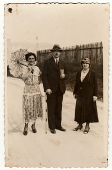 TRENCIANSKE TEPLICE, THE CZECHOSLOVAK REPUBLIC - CIRCA 1930s: Vintage photo shows women and man at the spa resort. One of the woman holds a parasol. Original retro black and white photography.