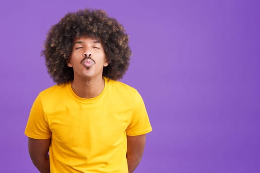 Stylish african man blowing a kiss with eyes closed in studio
