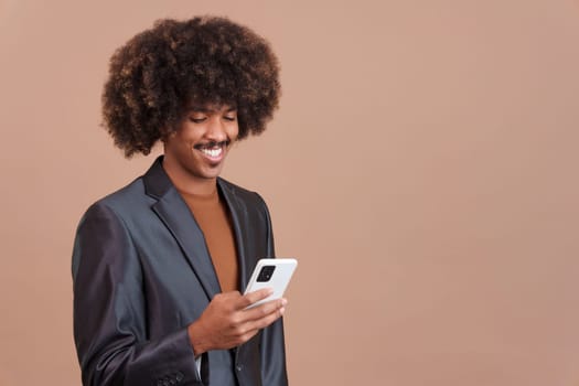 Happy stylish african man with curly hair using the mobile phone in studio