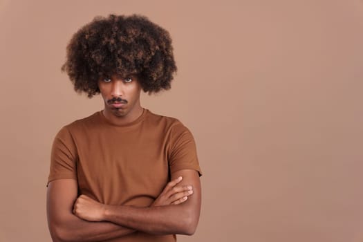 African man with afro hair crossing the arms while looking at camera with an angry expression in studio