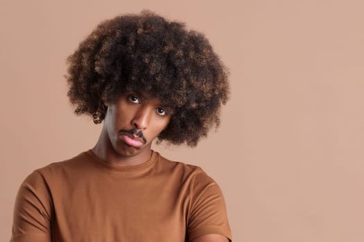 African man with curly hair looking at the camera with sad expression in studio