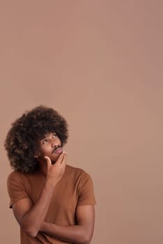 African man with curly hair and the hand on face and thoughtful expression in studio