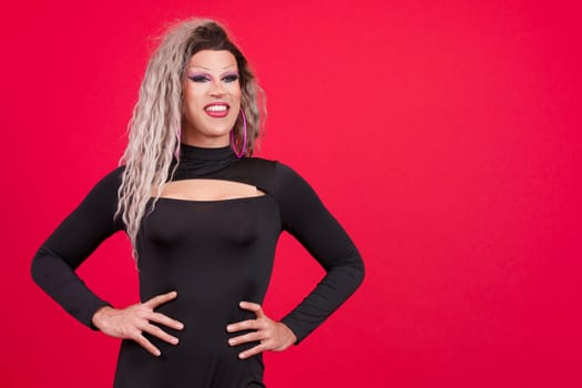 Relaxed transgender person with make up standing in studio with red background