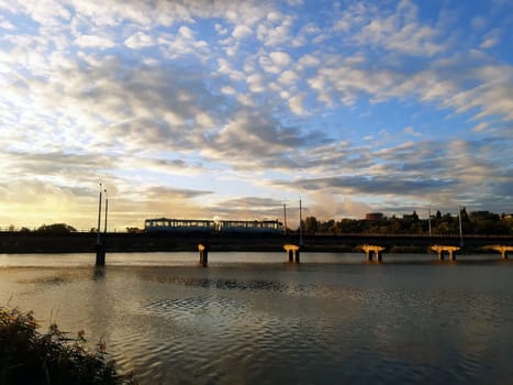 City high-speed tram on the bridge against the background of the morning sky and the rising sun.