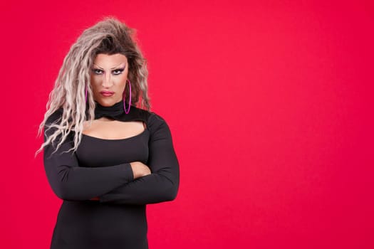 Transgender person crossing the arms with an angry expression in studio with red background