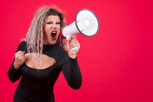 Angry transgender person shouting using a loudspeaker in studio with a red background