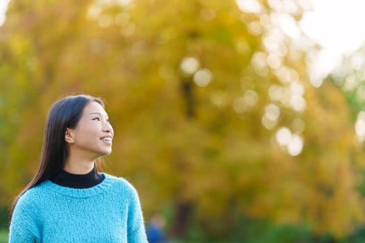 Photo with copy space of a distracted asian woman looking up in a park
