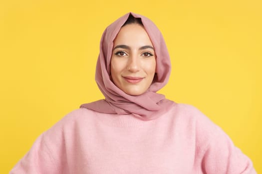 Beauty friendly muslim woman looking at camera in studio with yellow background