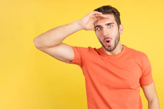 Surprised caucasian man looking at the camera in studio with yellow background