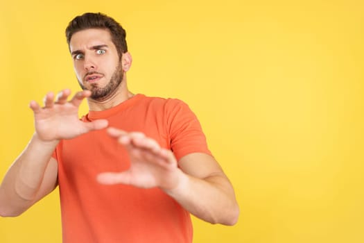 Caucasian man gesturing with the hands in fear in studio with yellow background