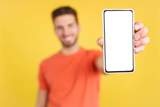Blank screen of the mobile held by a caucasian man in studio with yellow background