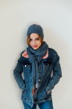 woman with a warm hat with a scarf in winter clothes stands on a white background